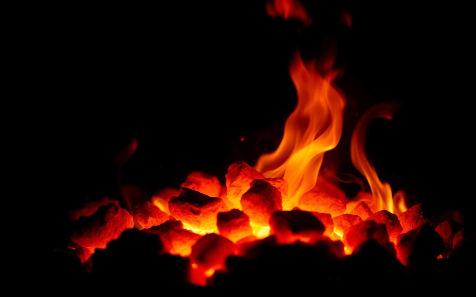 Glowing coals and flames inside a BOS BRAAI stainless steel fire box